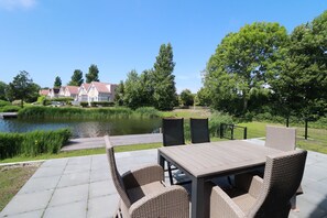 Eine Außenpatio mit Tisch und Stühlen, einem Teich und einem Zaun.
