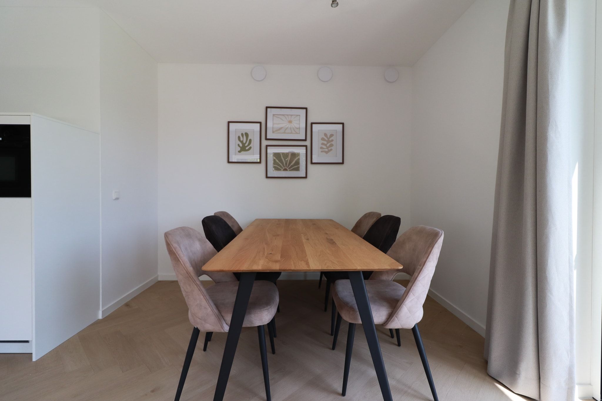 Ein Essbereich mit einem Holztisch, sechs Stühlen, einem Flachbildfernseher und gerahmten Bildern an der Wand.