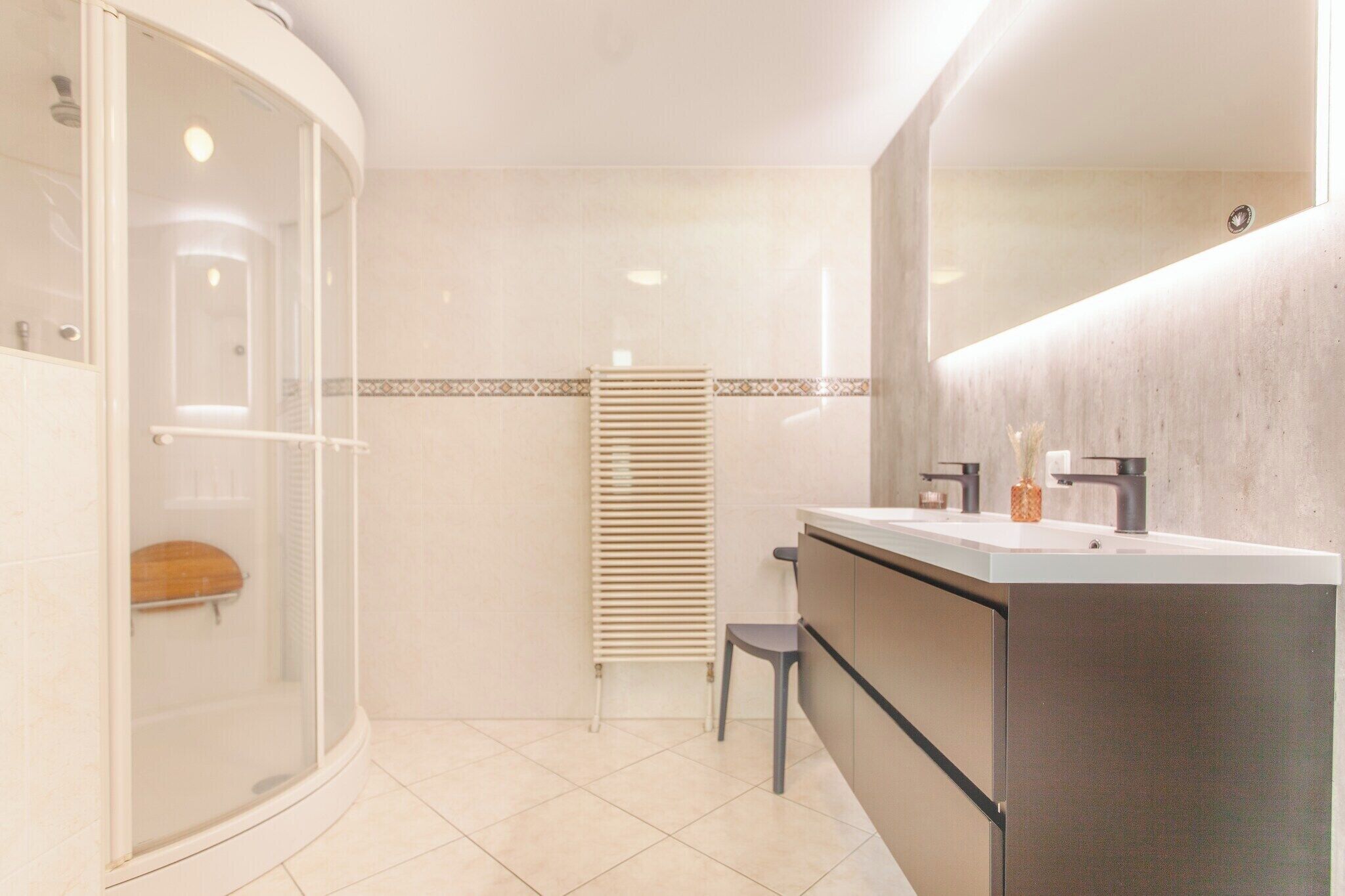 Un baño moderno con cabina de ducha de vidrio, lavamanos empotrado y toallero.