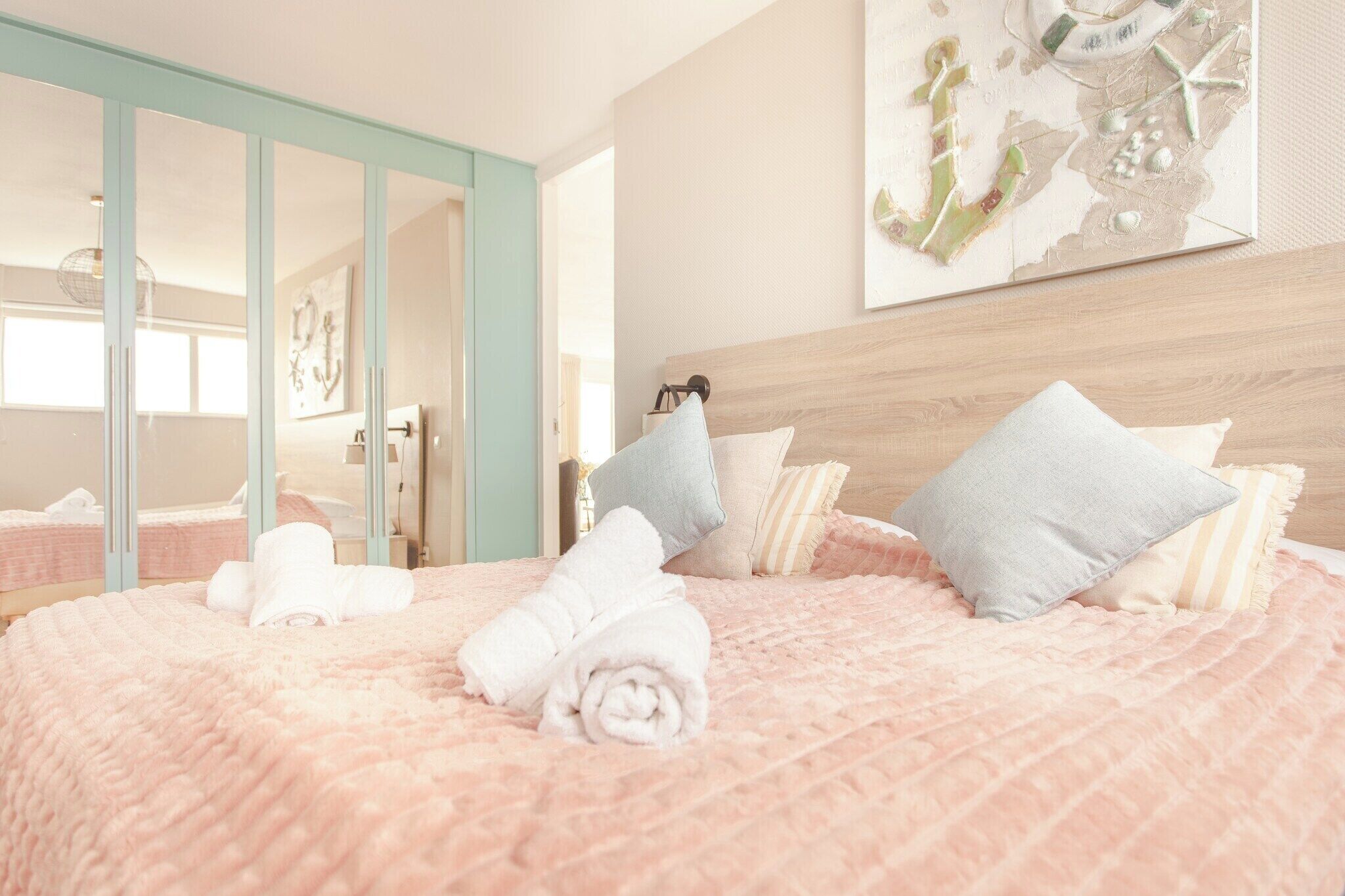 A bed with rolled towels, a wooden headboard, and a map artwork on the wall.
