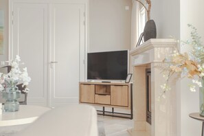 Een moderne woonkamer met een flatscreen televisie, een houten tv-meubel en een open haard.