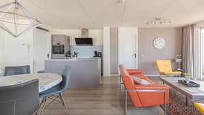 Un apartament modern amb cuina, zona de menjador i saló.