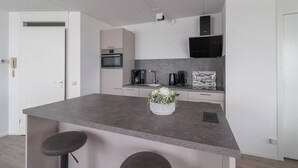 Una cocina moderna con una isla central, horno empotrado, microondas y campana extractora negra.
