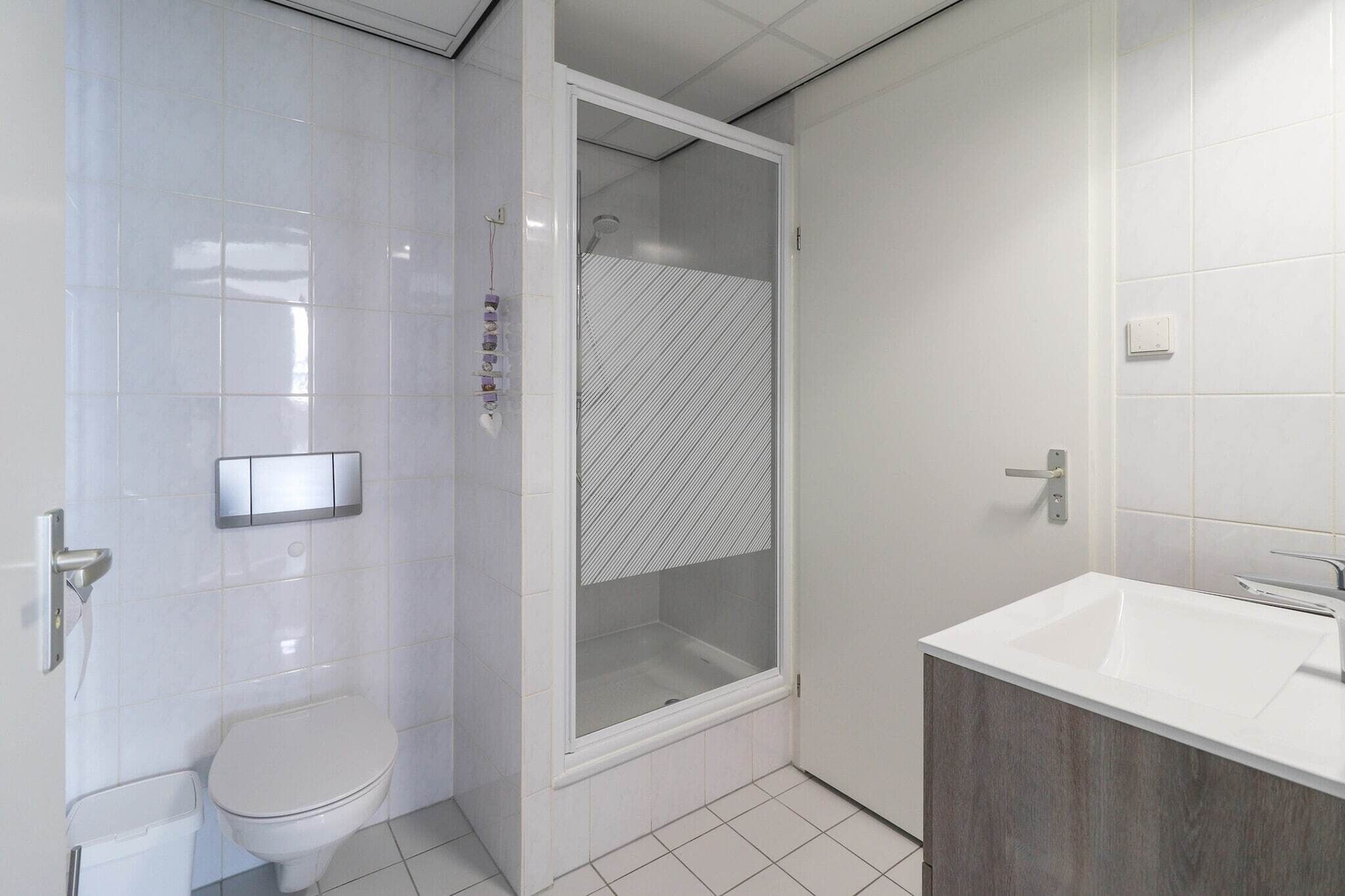 A bathroom with a toilet, a shower enclosure, and a sink.