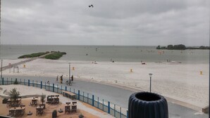 Una playa con un paseo marítimo, mesas y sillas.