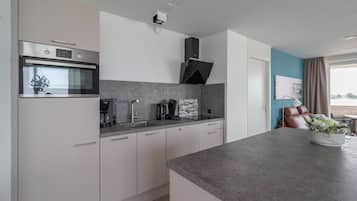 A modern kitchen with a built-in oven, a coffee maker, and a sink.