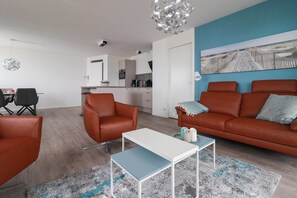 Una sala moderna con un sofá, sillones, una mesa de centro y un cuadro en la pared.