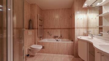 A bathroom with a bathtub, toilet, and two sinks.