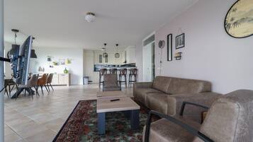 A modern living room with a sofa, a coffee table, and a dining area with chairs.