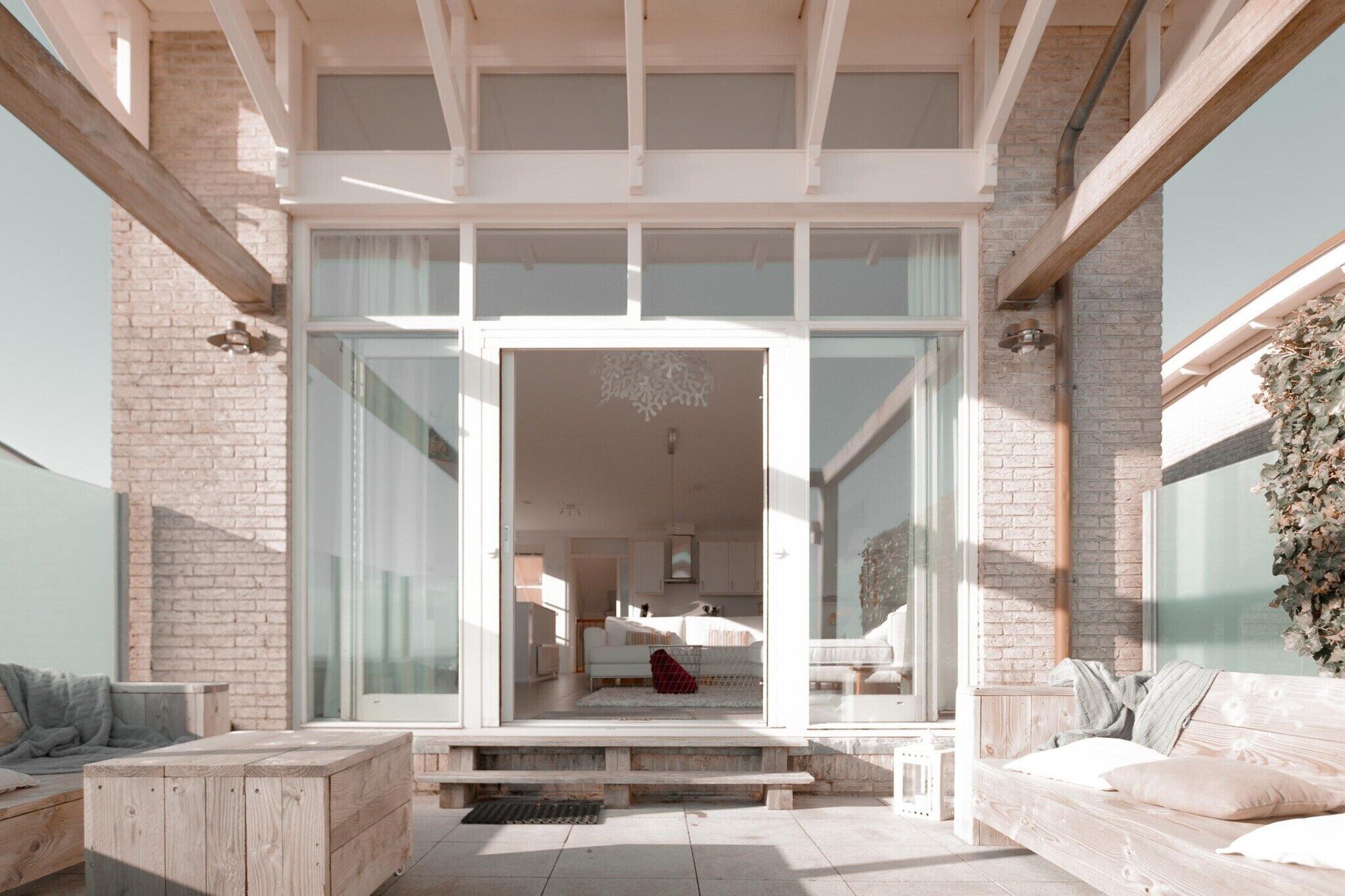 Un interior moderno con una entrada de puerta de vidrio que conduce a un espacio de sala de estar con un sofá y un gato.
