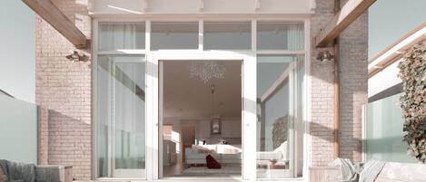 Un interior moderno con una entrada de puerta de vidrio que conduce a un espacio de sala de estar con un sofá y un gato.