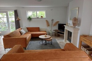Ein Wohnzimmer mit einem Ecksofa, einem kleinen runden Tisch, einem Kamin und einem Fernseher.