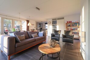 A modern living room with a sofa, chairs, a coffee table, and a bookshelf. - Attractive Dune Villa with Sauna (Makkum)