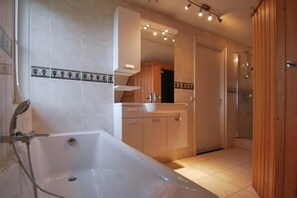 Een moderne badkamer met een vrijstaand bad, een wastafel met spiegel en een douchehoek.