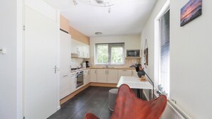Eine moderne Küche mit weißen Schränken, einer Mikrowelle und einem großen Fenster.