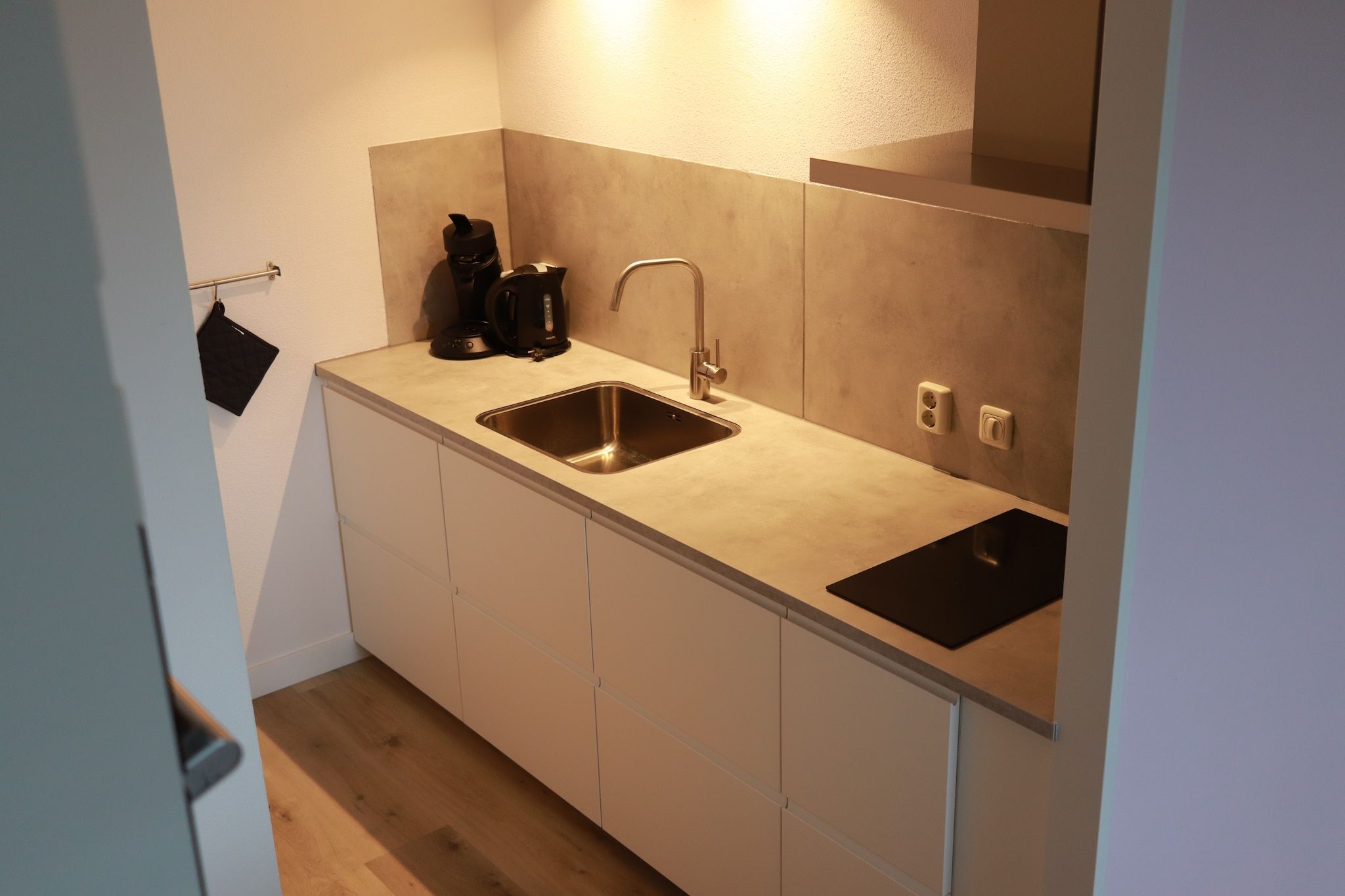 A compact kitchen with a double sink, a kettle, and a coffee maker.