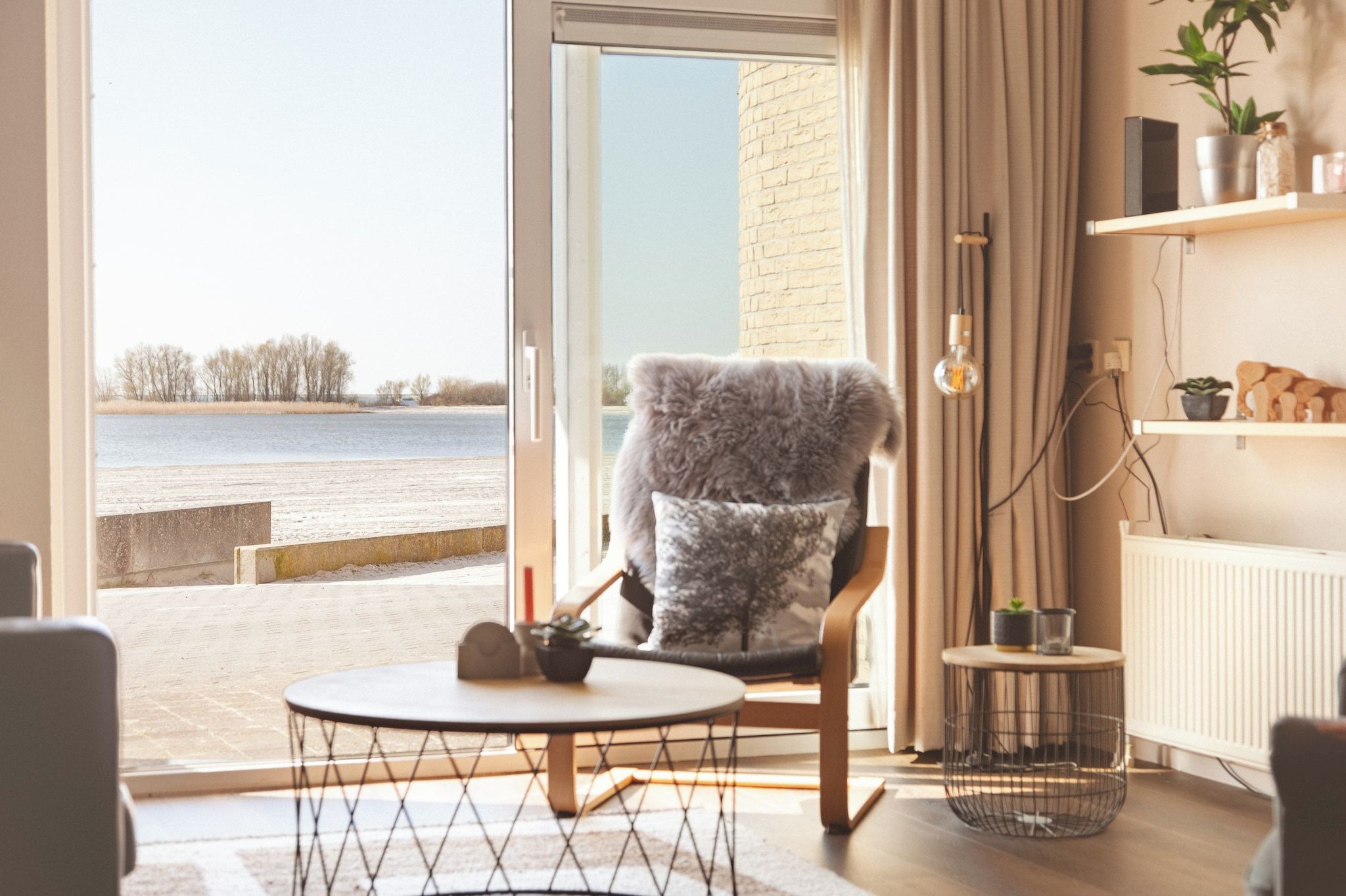 Une pièce avec vue sur un plan d’eau, comprenant une chaise, une table et une étagère ornée d’objets décoratifs.