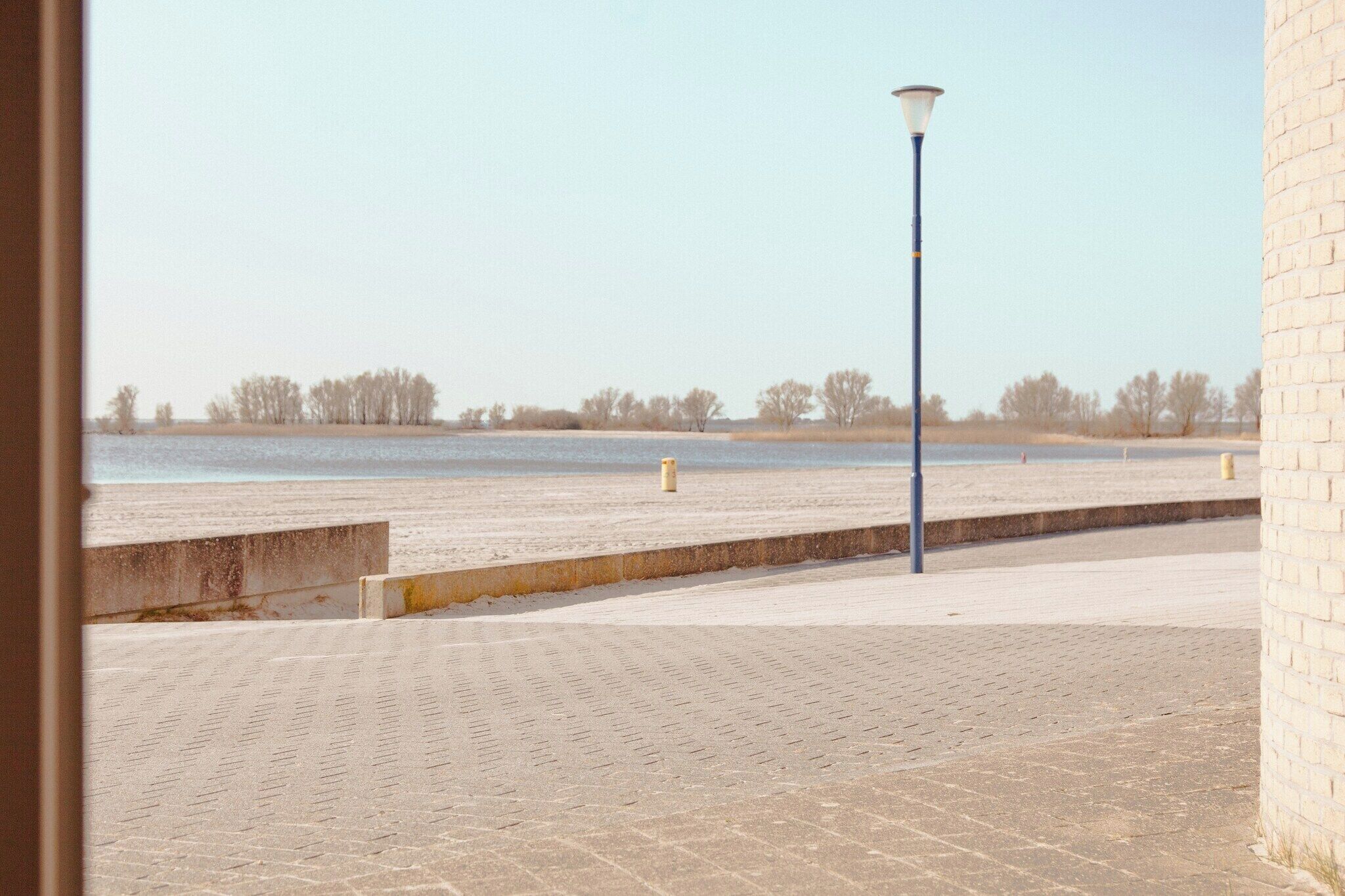 A paved walkway with a lamp post and a brick wall.