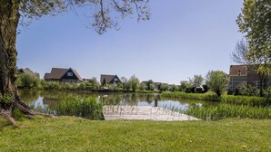 A tranquil lakeside setting with houses and a grassy area.