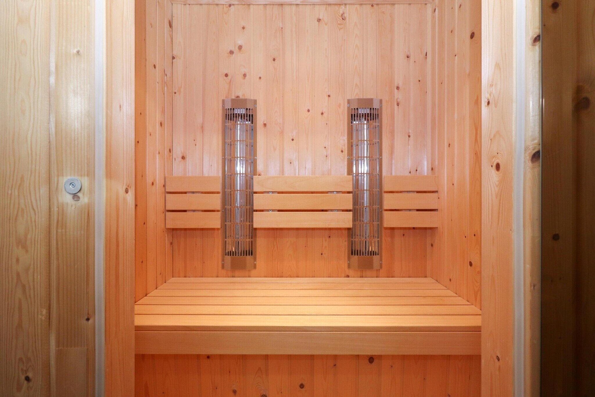A sauna with wooden benches and two visible steam vents.