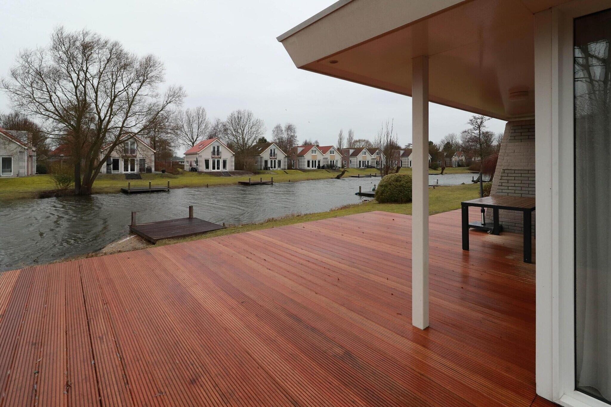A wooden deck with a view of houses across a river.