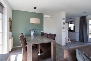 A modern living space with a dining table, seating, a kitchen area, and a sofa. - Luxury Waterfront Wellness Villa (Makkum)