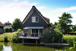 A house with a balcony, a pond in front, and a clear sky. - Luxury Waterfront Wellness Villa (Makkum)