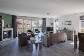 A modern living room with a fireplace, sofa, coffee table, and a television. - Luxury Waterfront Wellness Villa (Makkum)
