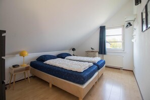 A bedroom with a bed, bedside tables, a lamp, a window with curtains, and a radiator. - Luxury Waterfront Wellness Villa (Makkum)