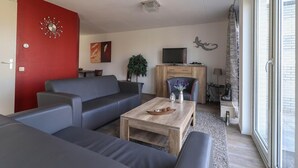 Un salon comprenant un canapé, une table basse, un téléviseur et une fenêtre donnant sur un beau paysage.