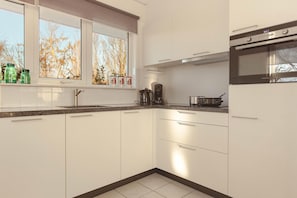 Eine moderne Küche mit weißen Schränken, einem eingebauten Ofen und einem Fenster mit Blick auf Bäume.