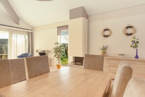 Ein stilvoller Essbereich mit Holztisch und -stühlen, einem Kamin und Blick ins Freie.