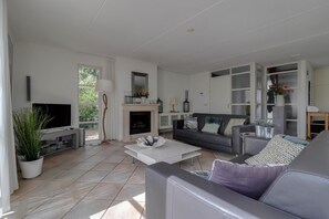 Ein modernes Wohnzimmer mit Kamin, Fernseher, Sofa und Couchtisch.