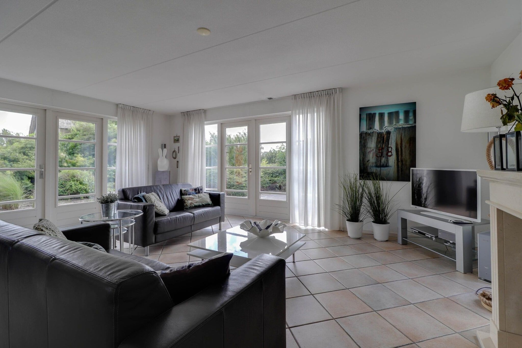 A modern living room with a sofa, coffee table, TV, and large windows.