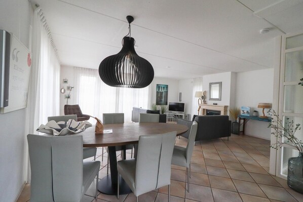 Een moderne woonkamer met een eethoek, een open haard en een televisie.