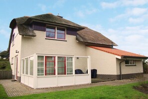 Ein zweistöckiges Haus mit Wintergarten, Strohdach und Ziegelaußenwand.