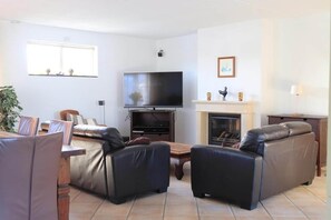 Ein Wohnzimmer mit einem Flachbildfernseher, einem Kamin und zwei Ledersofas.