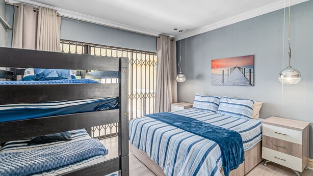 Quarto com beliches, mesa de cabeceira, abajur e um quadro na parede.