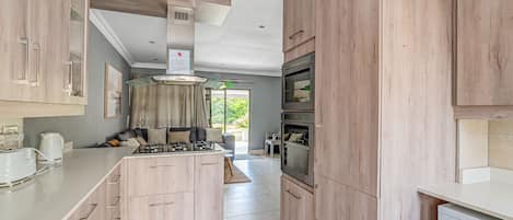 A modern kitchen with wooden cabinets, a central island, built-in oven, and a dishwasher.