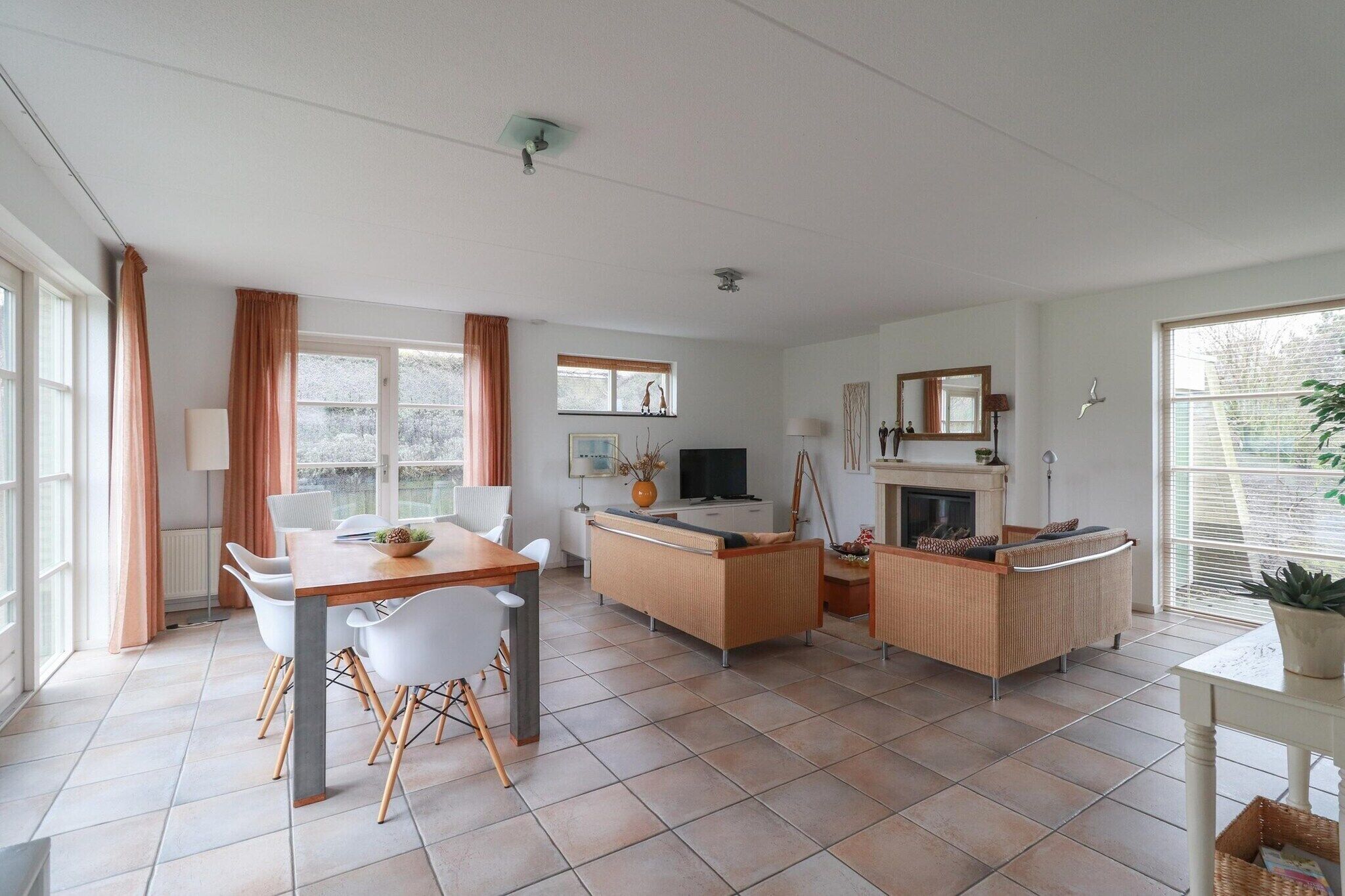 A spacious living area with a dining table, sofas, and a fireplace.