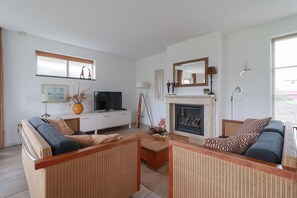 Ein Wohnzimmer mit einer Couch, einem Fernseher, einem Kamin und einem Esstisch.