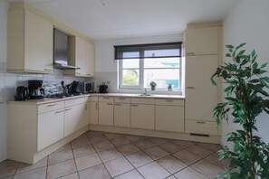 Eine Küche mit hellen Schränken, einem Fenster mit Ausblick und einem Blumentopf.