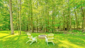 Une zone boisée avec deux fauteuils Adirondack et un foyer circulaire.