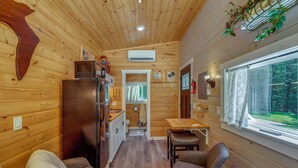 Un intérieur de cabine compact comprenant un coin cuisine, un espace repas et une fenêtre donnant sur un paysage verdoyant.