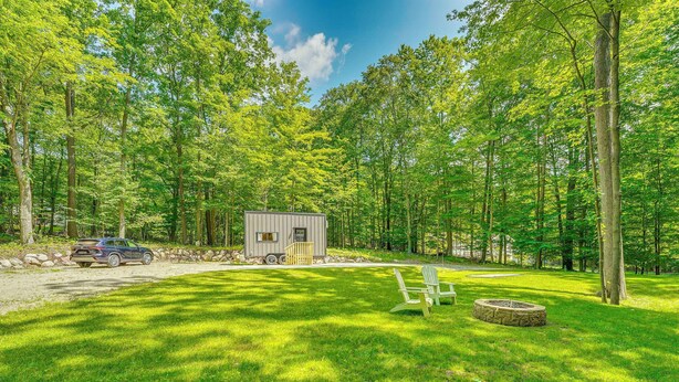 Une cabane avec une petite terrasse et un foyer, située dans une zone boisée.