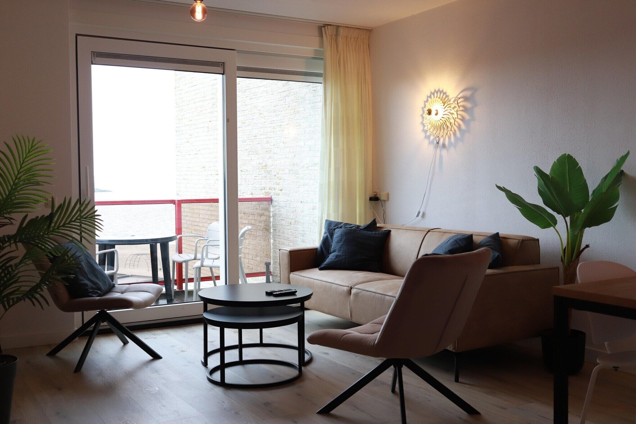 Un salon moderne avec un canapé, des fauteuils, une table basse et un balcon offrant une vue agréable.