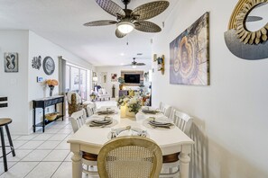 A dining area with a white table set for six, surrounded by white chairs, with a ceiling fan above. - Pool, Fishing Dock! Port Charlotte Canal-Front Gem (Port Charlotte)