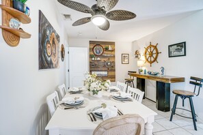A dining area with a white table set for six, a ceiling fan, and nautical-themed decor. - Pool, Fishing Dock! Port Charlotte Canal-Front Gem (Port Charlotte)