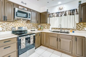 A kitchen with a stove, microwave, and sink. - Pool, Fishing Dock! Port Charlotte Canal-Front Gem (Port Charlotte)