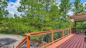 A wooden deck with a railing, a covered seating area, and a sign that reads 'The Porch.'